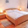 Cozy bedroom with double bed, wooden floor and bedside tables with lamps.
