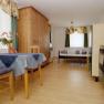 Kleine Wohnung mit Holzm&ouml;beln, Esstisch, St&uuml;hlen, Bett und K&uuml;chenzeile.