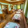 Gem&uuml;tliches Restaurant mit Holzm&ouml;beln und Tischdecken, dekoriert mit Geweihen an den W&auml;nden.