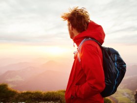 Ein Wanderer genie&szlig;t den atemberaubenden Sonnenuntergang &uuml;ber den majest&auml;tischen Bergen. Die sanften H&uuml;gel und die weite Landschaft laden zu unvergesslichen Erlebnissen in der Natur ein. Hier, wo die Luft frisch und klar ist, wird jeder Schritt zum Abenteuer.