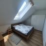 Modern bedroom with skylight, double bed, wooden furniture and white closet.