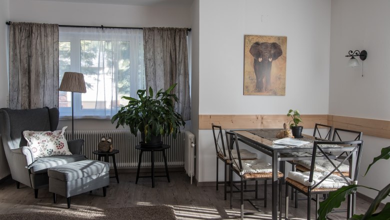 Gem&uuml;tliches Wohnzimmer mit Sessel, Tisch und Pflanzen.