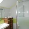Modernes Badezimmer mit Waschbecken, Holzschrank und Dusche mit Glaswand.