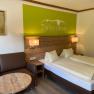 Cozy double room with wooden furniture, sofa, table and wall decoration.