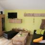 Modernes Wohnzimmer mit gelber Wand, schwarzem Sofa, Holzm&ouml;beln und Dekorationen.