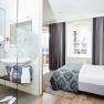 Modern hotel room with double bed and glass shower.