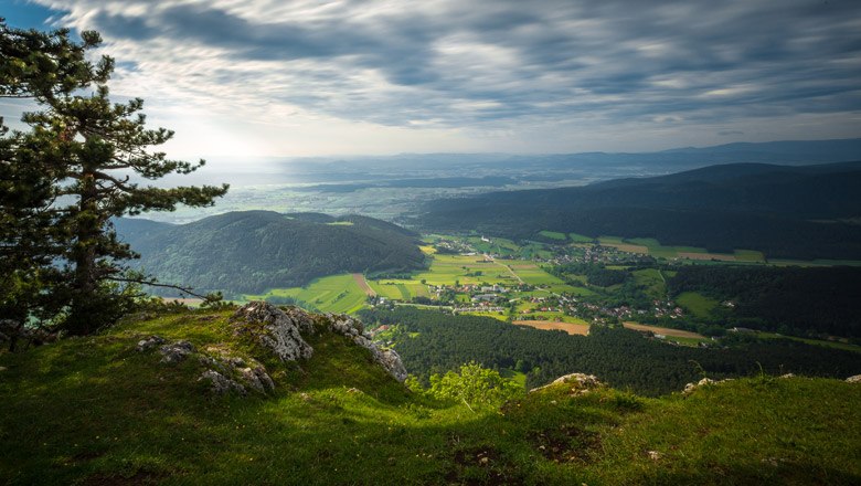 View from a cliff edge of a green landscape with hills and a village in the valley.