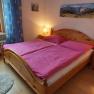 Gem&uuml;tliches Doppelzimmer mit Holzbett, pinker Bettw&auml;sche und Nachttischen mit Lampen.