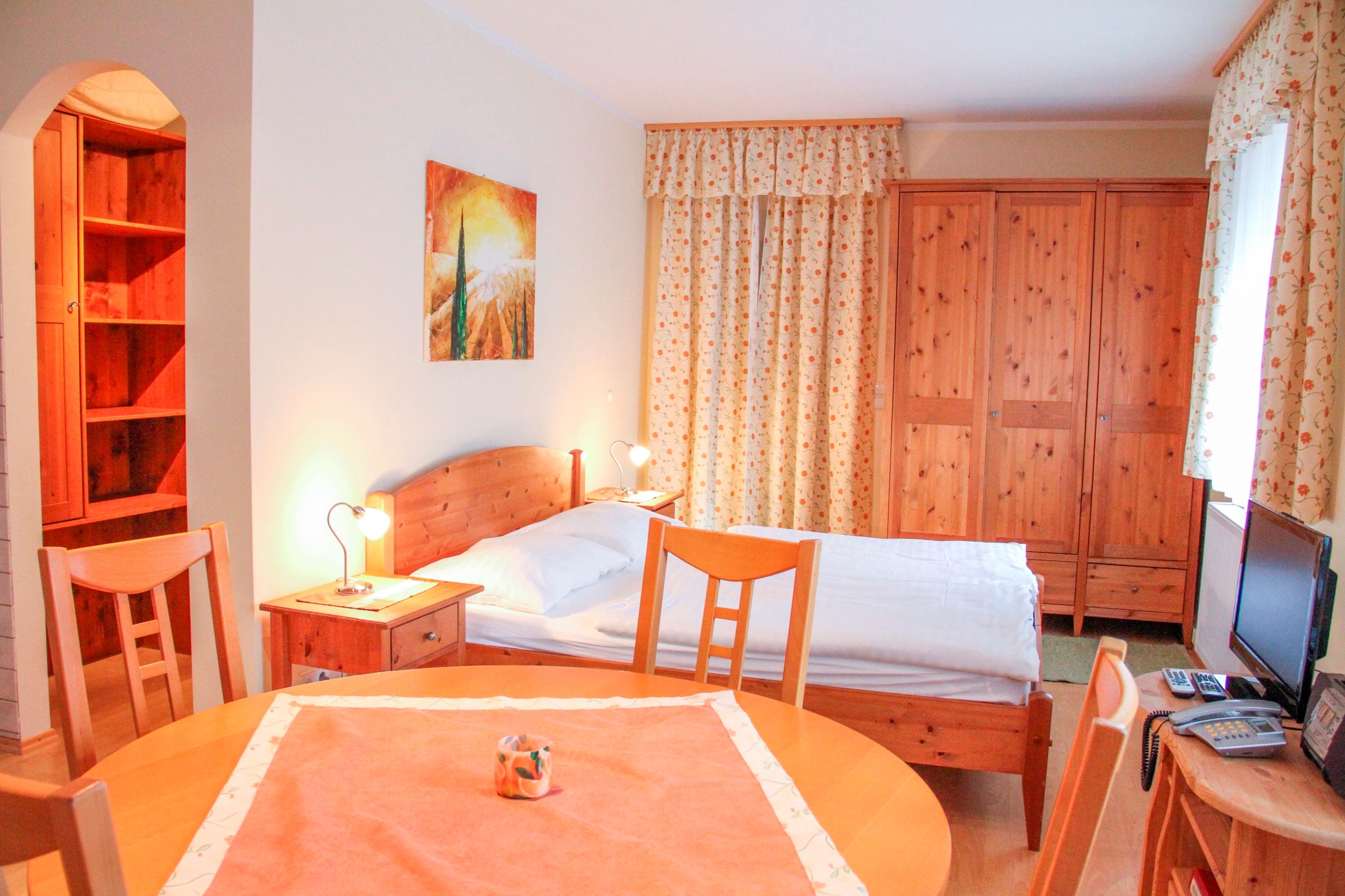 Kleine Wohnung mit Holzmöbeln, Bett, Tisch und Schrank.