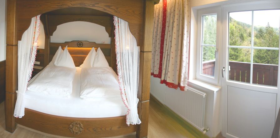 Gemütliches Schlafzimmer mit Himmelbett und Balkonblick ins Grüne.