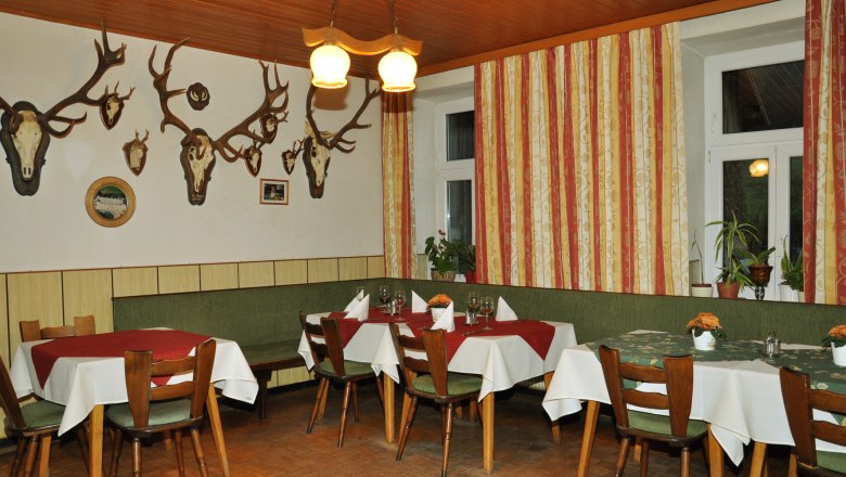 Interior view of a traditional inn with wooden furniture and antlers on the wall.
