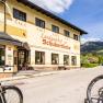 Bicycles in front of a yellow country inn with mountains in the background.