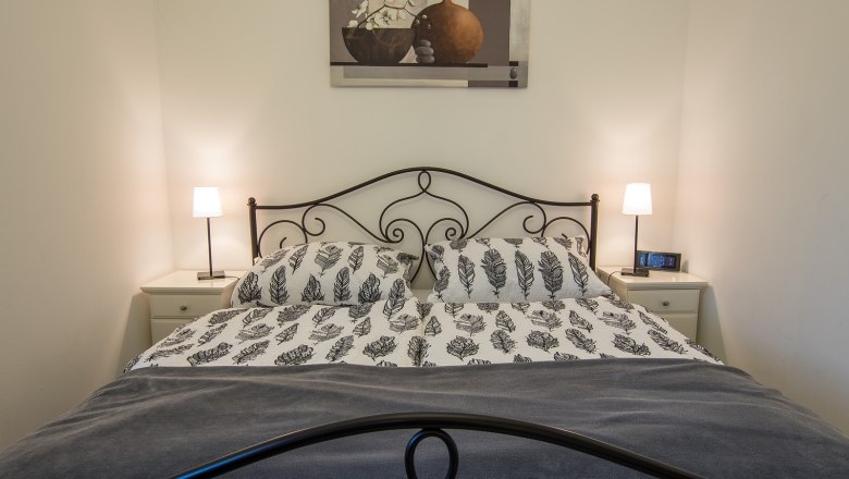 Bedroom with double bed, two bedside tables and lamps.