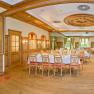 Eleganter, holzverkleideter Speisesaal mit gedeckten Tischen und gro&szlig;en Fenstern.