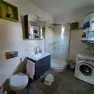 Modernes Badezimmer mit Dusche, Waschbecken, Toilette und Waschmaschine.