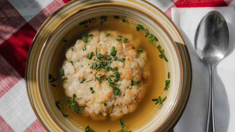 Klare Suppe mit Grie&szlig;nockerl in einem Teller auf karierter Tischdecke beim Damb&ouml;ckhaus am Schneeberg