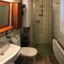 Kleines Badezimmer mit Dusche, Waschbecken, Toilette und Holzschr&auml;nken.