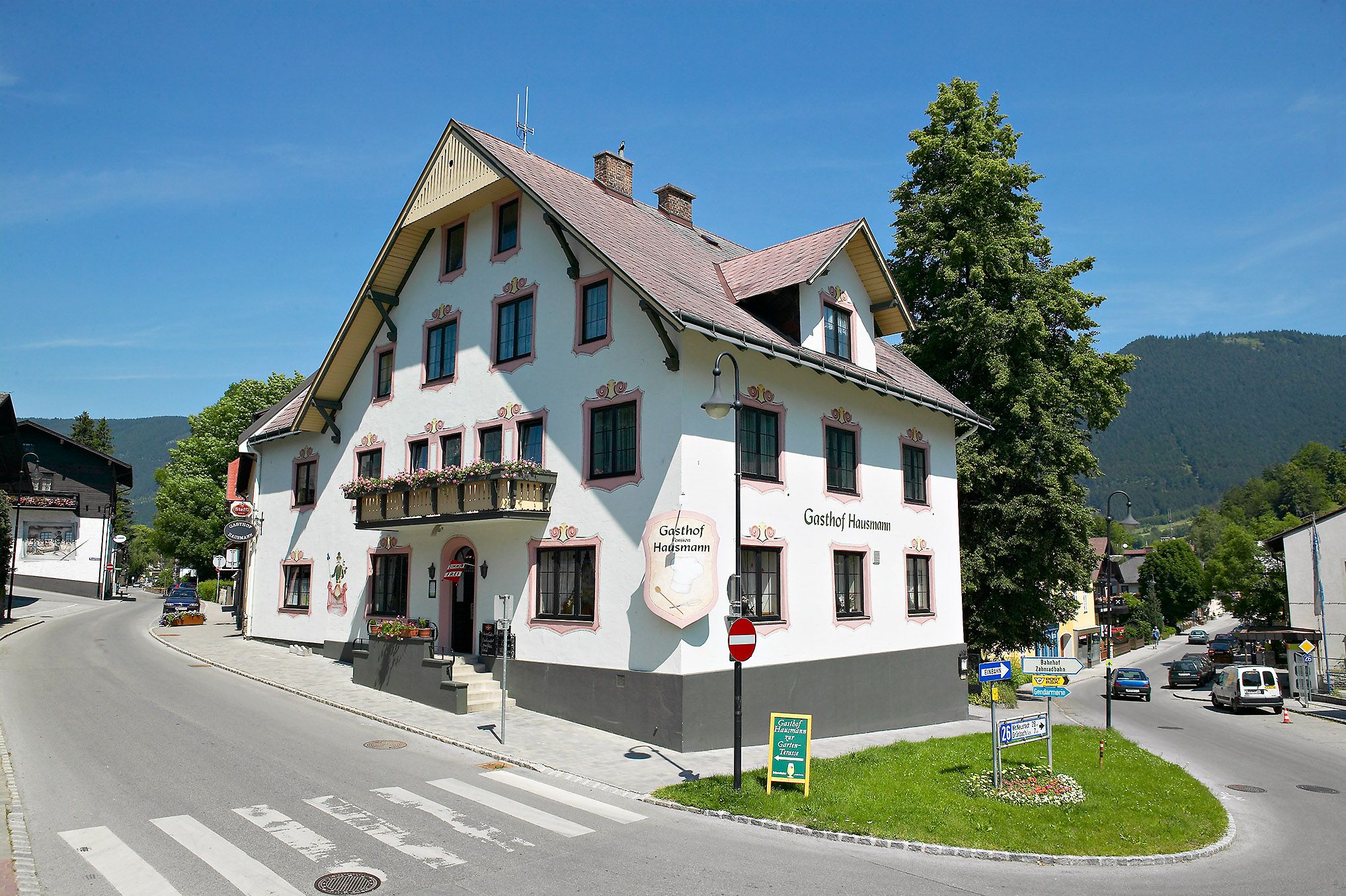 Ein traditioneller Gasthof an einer Straßenecke in einer ländlichen Umgebung.