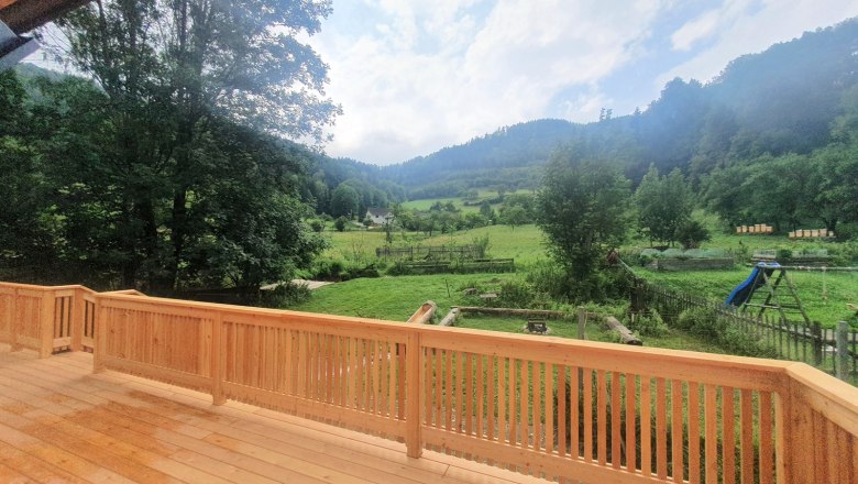 View from a terrace of a green landscape with trees and hills.