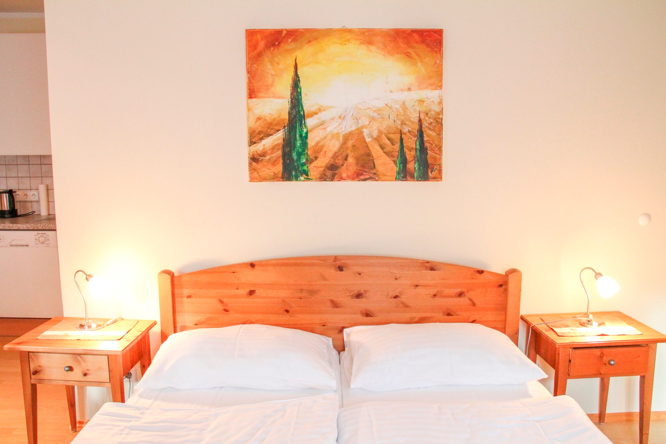 Schlafzimmer mit Holzbett, zwei Nachttischen und einem Landschaftsbild an der Wand.