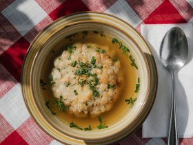 Klare Suppe mit Grie&szlig;nockerl in einem Teller auf karierter Tischdecke beim Damb&ouml;ckhaus am Schneeberg