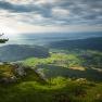 View from a cliff edge of a green landscape with hills and a village in the valley.