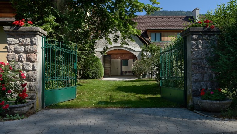 A nyitott z&ouml;ld kapu egy kertes h&aacute;zhoz vezet.