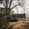 Hotel Schneeberghof in the sunlight with trees in the foreground.