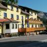 Yellow inn with wooden balconies and a mountain in the background.