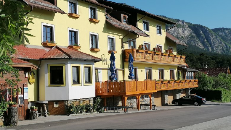 Yellow inn with wooden balconies and a mountain in the background.