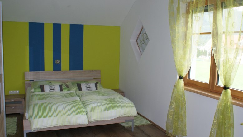 H&aacute;l&oacute;szoba francia&aacute;ggyal, z&ouml;ld &eacute;s s&aacute;rga cs&iacute;kos fal, z&ouml;ld f&uuml;gg&ouml;ny&ouml;k, fapadl&oacute;.