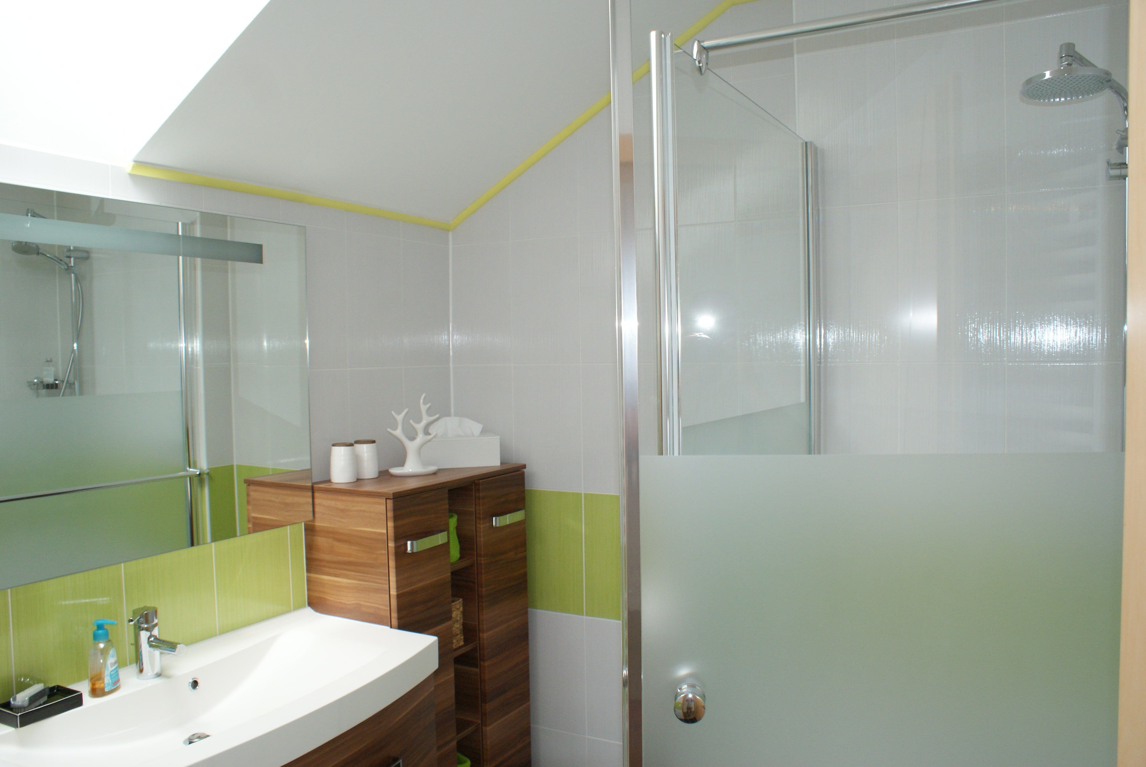 Modernes Badezimmer mit Waschbecken, Holzschrank und Dusche mit Glaswand.